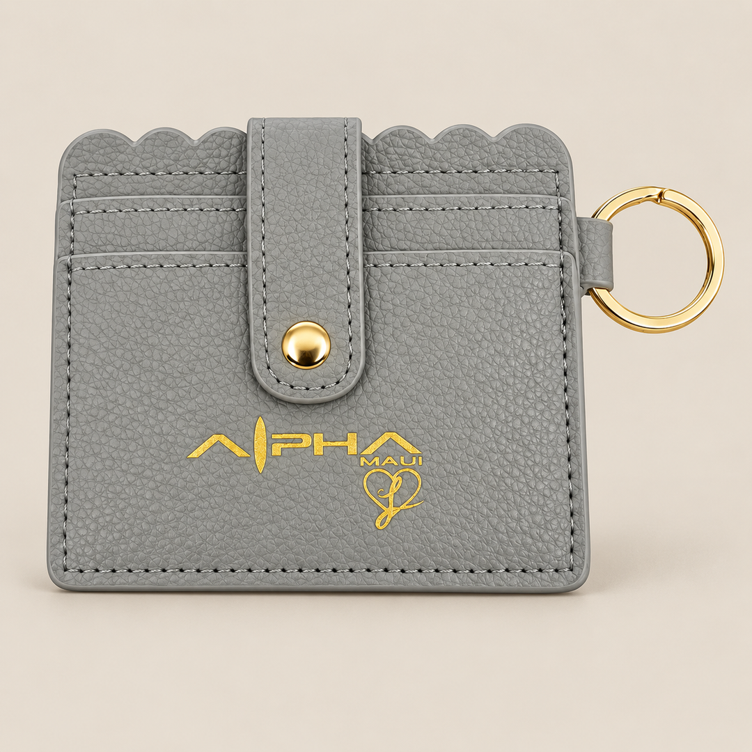 Alpha Maui gray leather wallet with gold logo and key ring on sand background