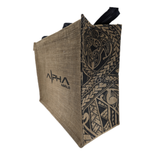 The Alpha Jute Bag is a brown, rectangular tote adorned with "Alpha Maui" branding on the side. This stylish bag showcases intricate black tribal designs along the side panel and features sturdy black handles, capturing the essence of Aloha. It’s ideal for carrying beach apparel and other essentials for your Ohana outings.