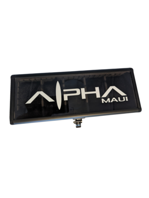 A rectangular sign with a black background displays the text "Alpha WATCH CARRIER" in white uppercase letters. The letter "L" is stylized to resemble a surfboard or fin shape, evoking a sense of Aloha. The elevated sign likely advertises watch carriers or serves as a business identifier.