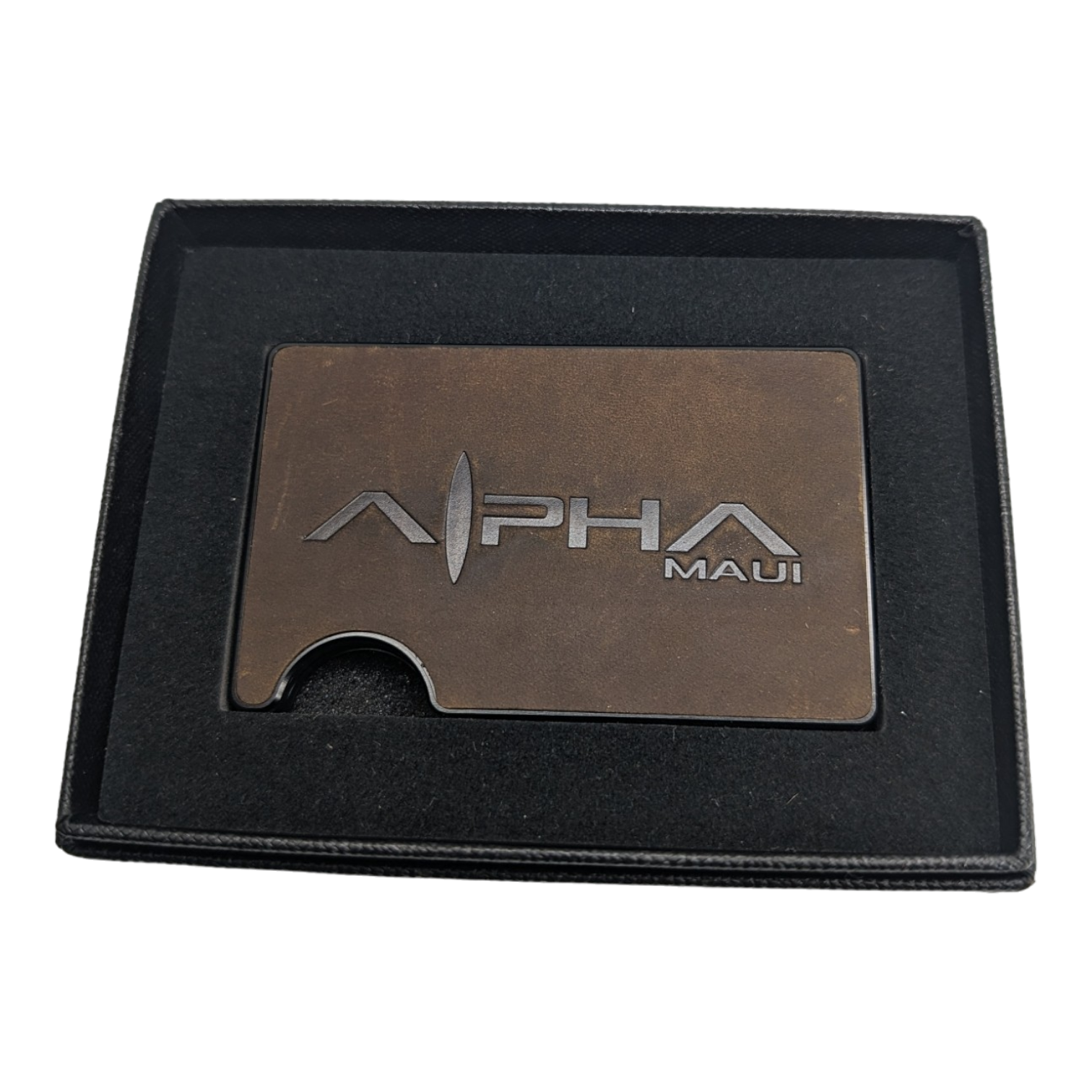 An elegant dark brown metallic card holder featuring the text "Alpha Clip Leather" engraved on it. The card holder is presented in a black box with a luxurious dark lining, making it an ideal gift or presentation item—a perfect accessory for enthusiasts of Hawaii and beach apparel culture.