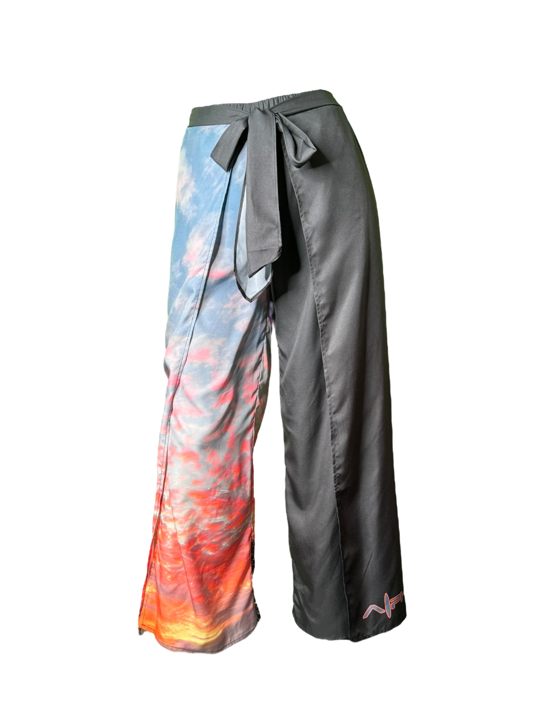 Introducing the Alpha Maui Pukalani Wrap Pants, a pair of unique wide-legged pants featuring a stunning split design perfect for beach apparel. The left leg boasts a vibrant sky and cloud print transitioning from blue to orange, capturing the essence of an Alpha Maui sunset, while the right leg is solid black. These pants are completed with a stylish tie-waist closure.