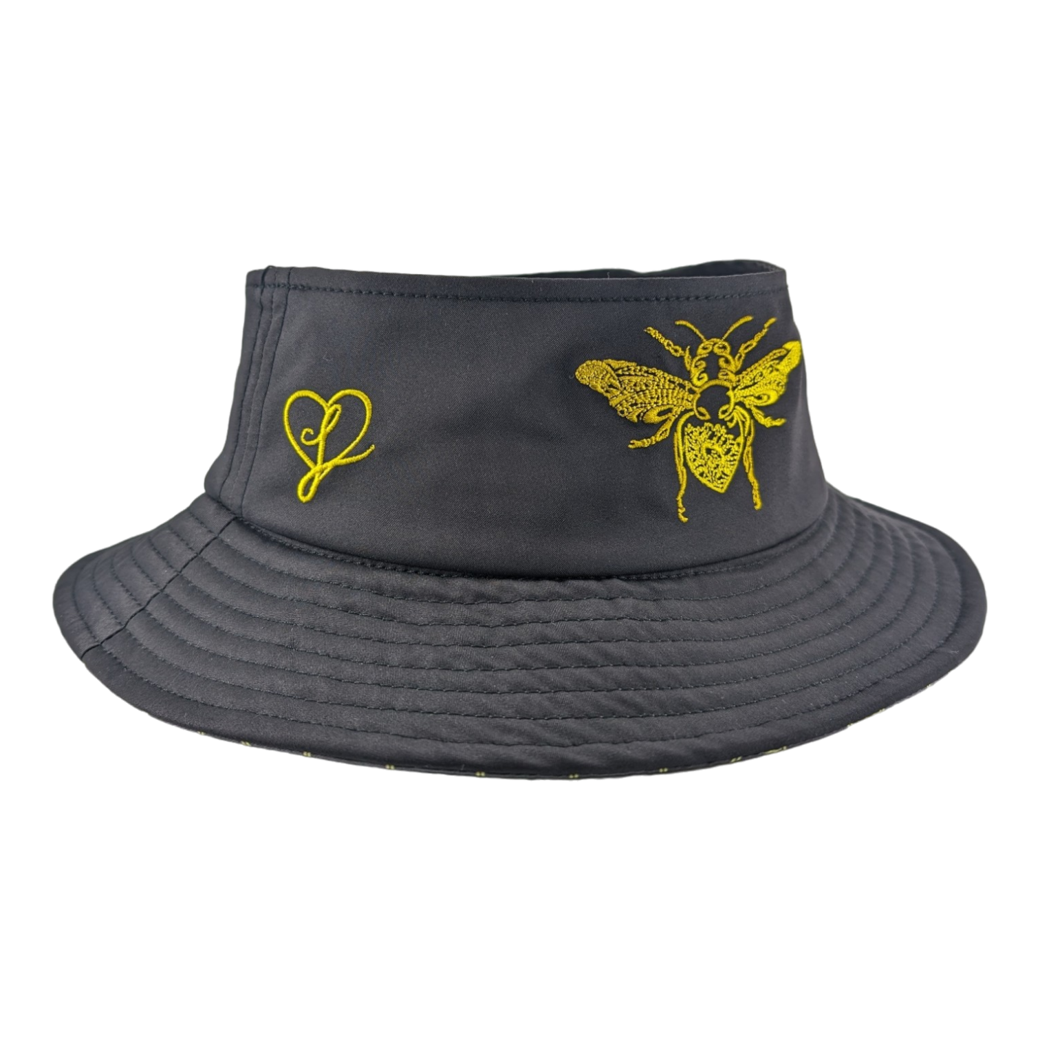 A dark gray bucket hat with yellow embroidery featuring a detailed bee and a heart with a line through it. The hat has a wide, stitched brim and a simple, stylish design.