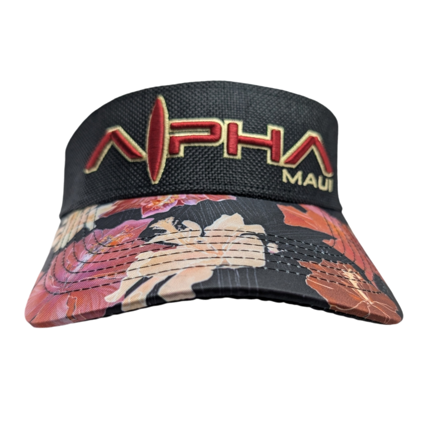 A black visor cap with "Alpha Maui" embroidered in red and gold on the crown. The brim features a colorful floral pattern with shades of pink, orange, and beige on a black background.