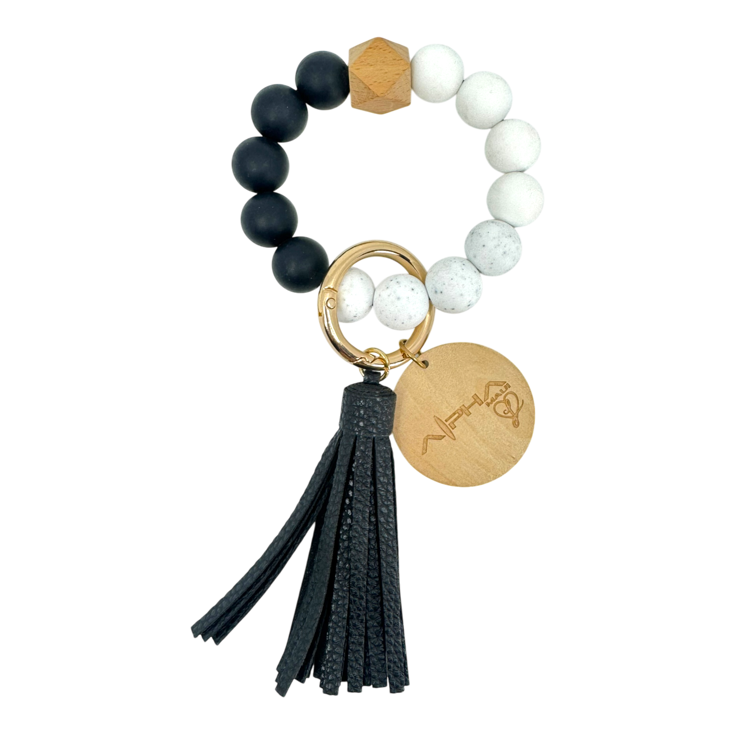 A stylish keychain featuring a bracelet made of alternating black and white beads, a wooden hexagonal bead, and a gold ring attached to a black tassel and wooden charm with an engraved design.